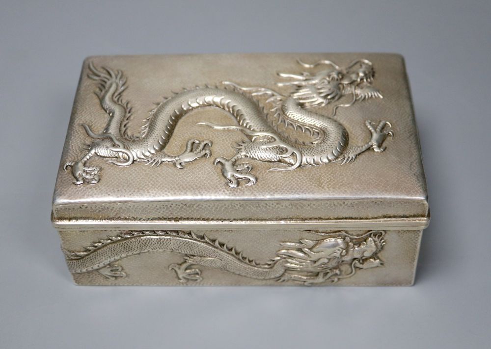 An early 20th century Chinese Export white metal cigarette box, embossed with a dragon, by Wang Hing, 13cm, gross 9oz.